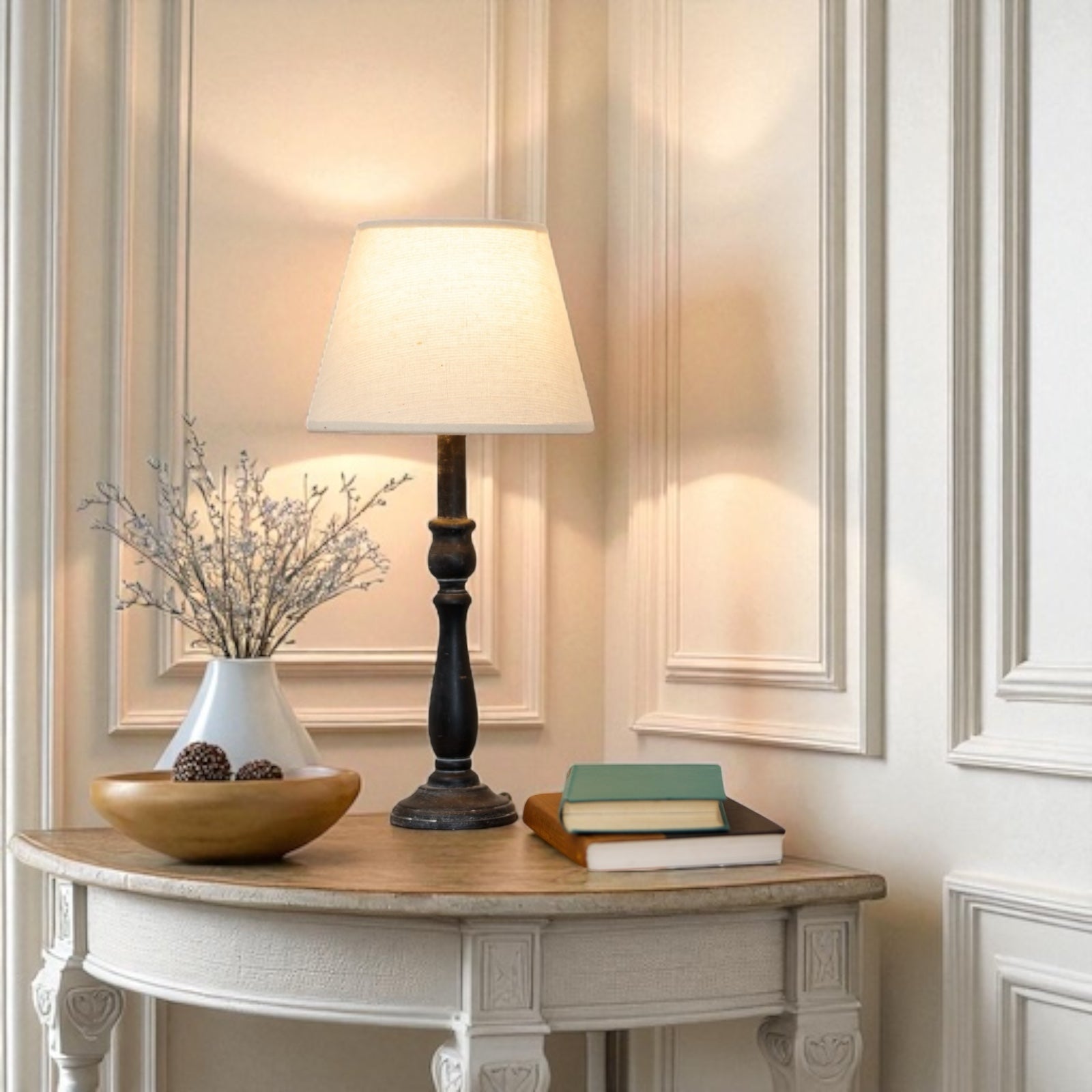 Decorative table with lamp, books, and vase against a wall with paneling