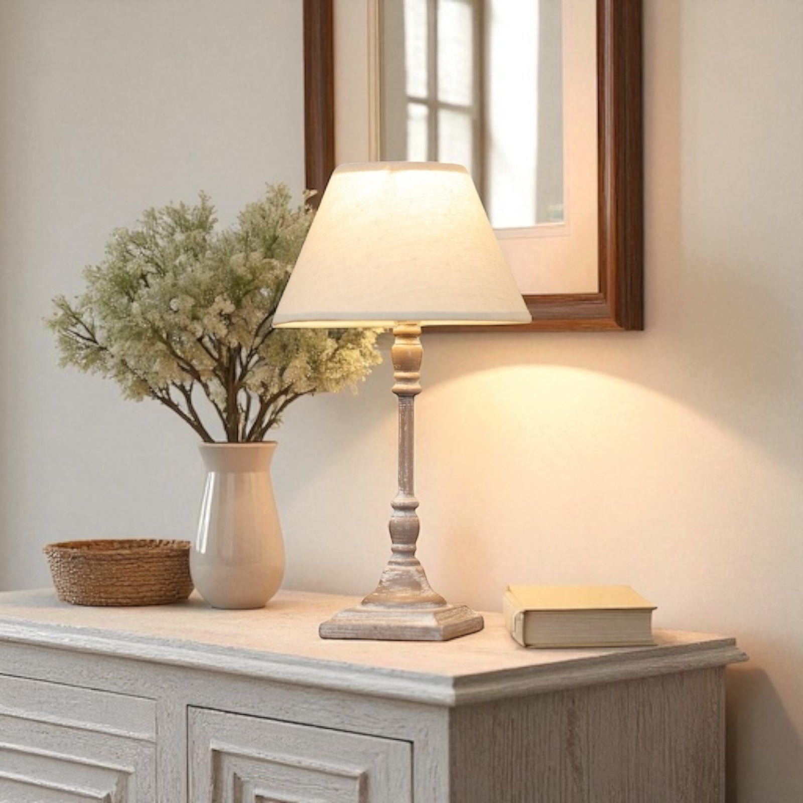 Almira Table lamp on a wooden side table with a vase of flowers and a book in a softly lit room.