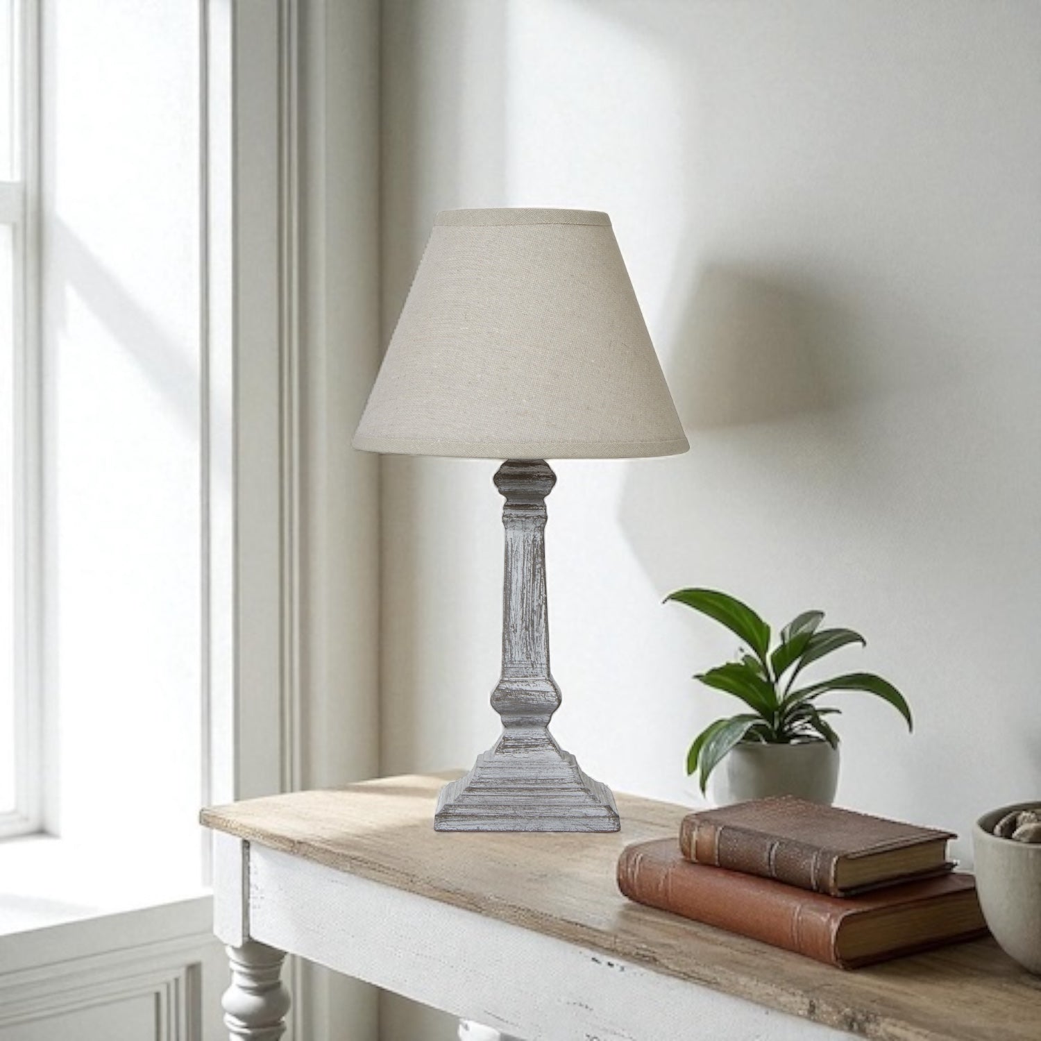 Anika Table lamp on a wooden surface with books and a plant in a bright room.