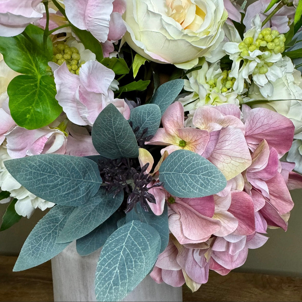 Bouquet of pink, white, and green flowers with green leaves.