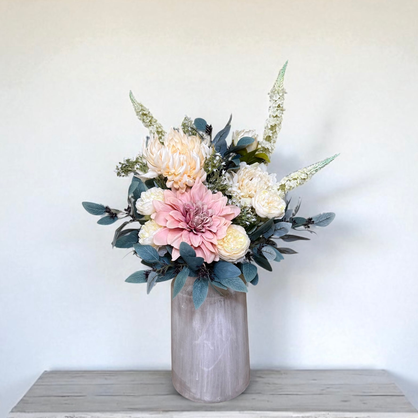 Floral arrangement in a textured vase on a white surface with a light background