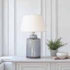 Decorative lamp with a textured blue base on a white surface against a white panelled wall.