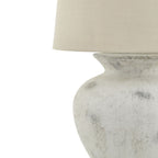 Table lamp with a textured white base and cream lampshade on a white background