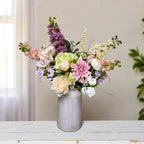 Floral arrangement in a gray vase on a wooden surface with a neutral background