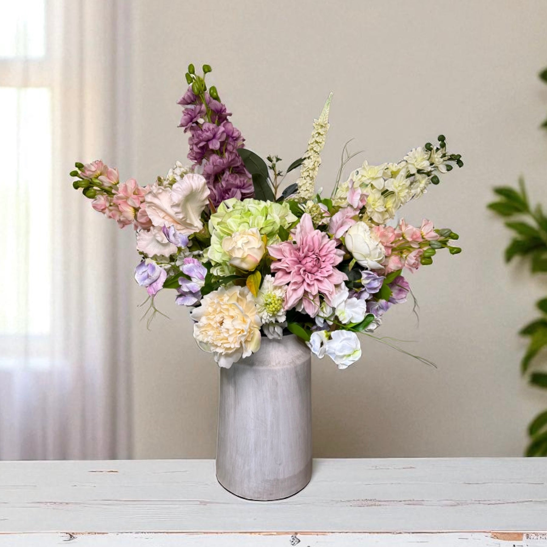Floral arrangement in a gray vase on a wooden surface with a neutral background