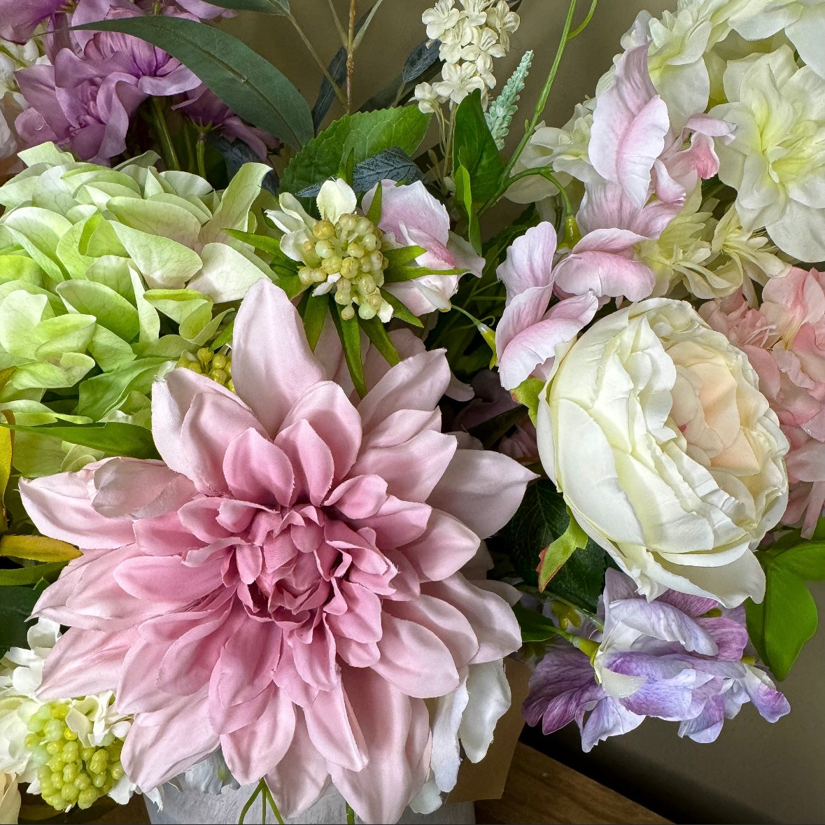 Bouquet of pink, white, purple and green flowers with green leaves.