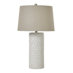 Table lamp with textured white base and cream lampshade on a white background