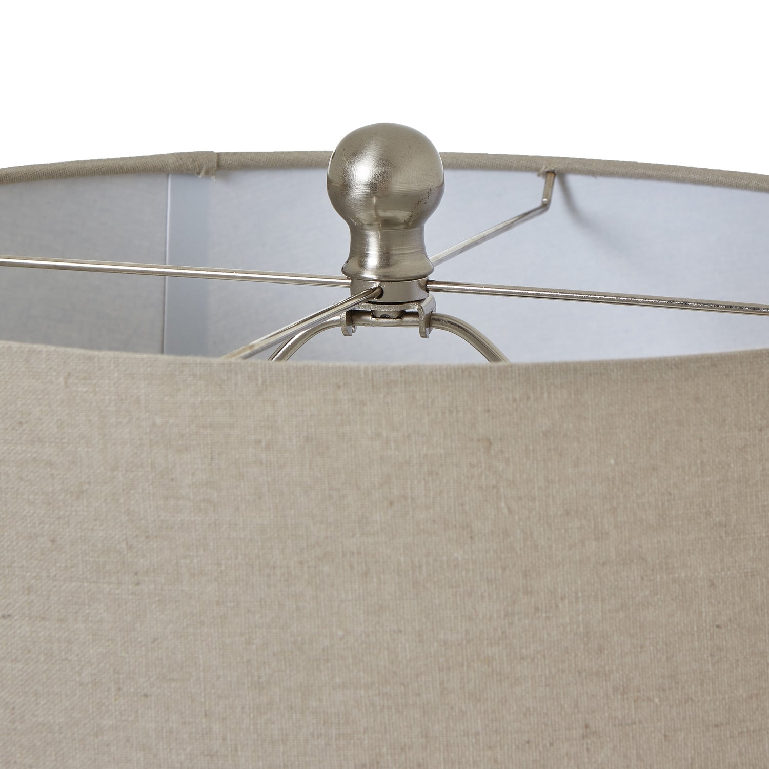 Close-up of a lampshade with a cream fabric shade and metallic fixture.