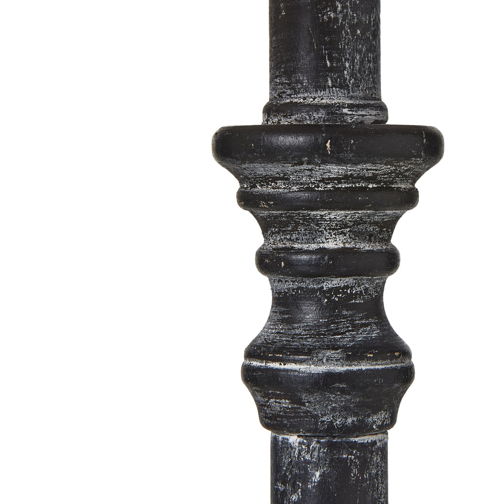 Close-up of dark wood table lamp stem with decorative top on a white background