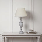 Table lamp on a wooden table against a white paneled wall