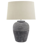 Table lamp with textured dark grey base and cream lampshade on a white background
