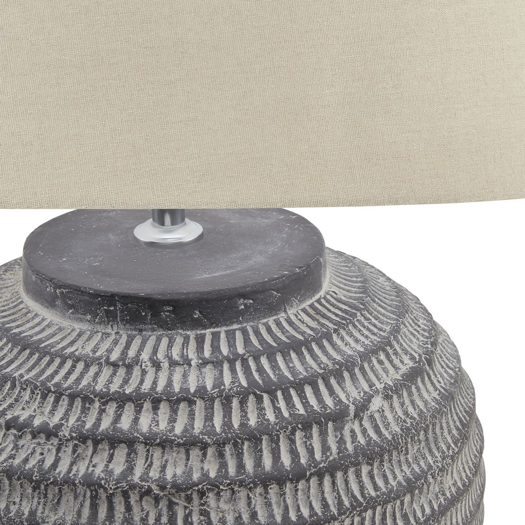 Close-up of a textured lamp base with a cream lampshade in the background