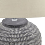 Close-up of a textured lamp base with a cream lampshade in the background