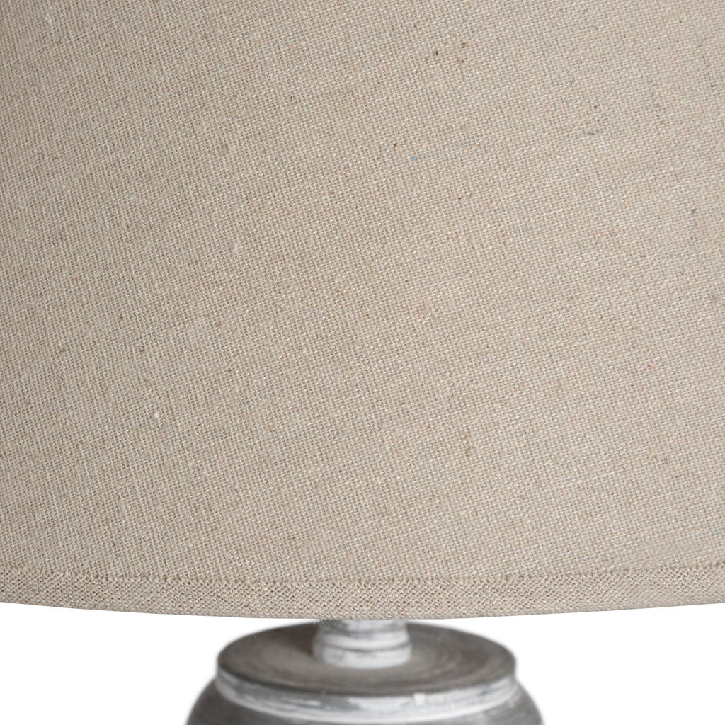 Close-up of a cream lampshade with a grey floor lamp base on a white background