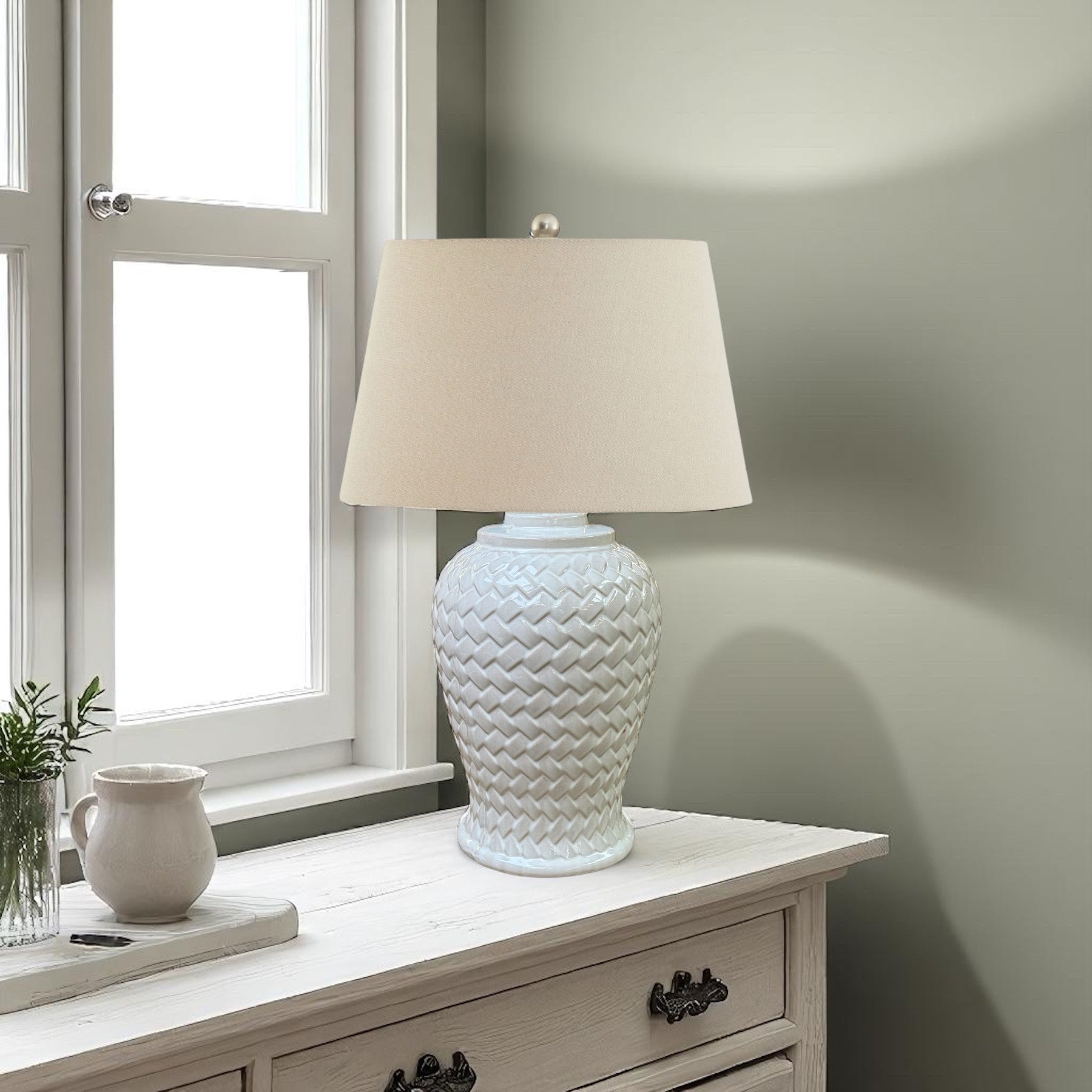 White woven textured table lamp on a wooden side table with a window in the background