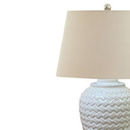 Table lamp with woven design base and cream lampshade on a white background