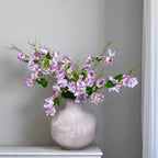 Light grey vase with purple sweet pea flowers on a grey background