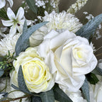 Close-up of a bouquet with white roses, greenery, and other flowers.