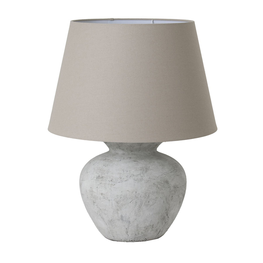 Table lamp with a textured white base and a beige lampshade on a white background