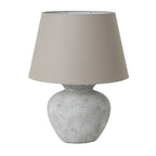 Table lamp with a textured white base and a beige lampshade on a white background