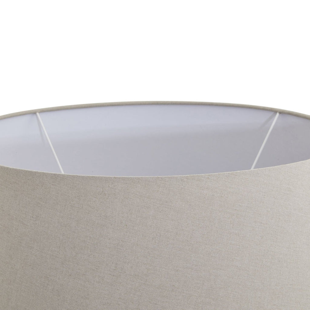 Close-up of a lampshade with a white inner rim and beige outer fabric.