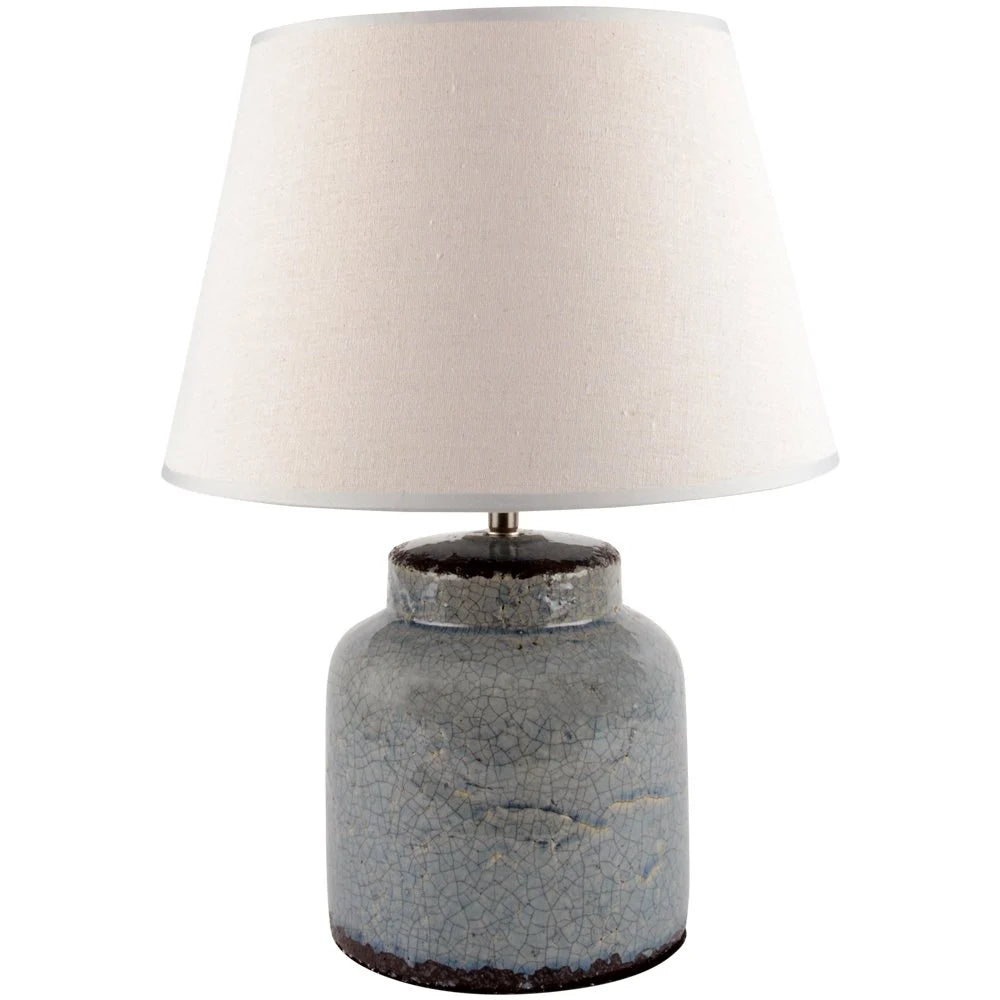 Table lamp with textured blue base and cream lampshade on a white background