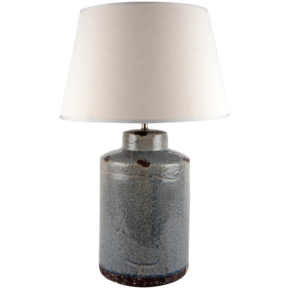 Table lamp with a textured ceramic blue base and cream lampshade on a white background